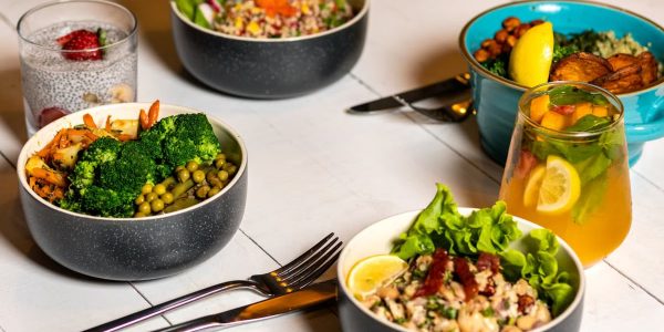 A vibrant assortment of healthy bowls and drinks showcasing fresh ingredients like broccoli and citrus.